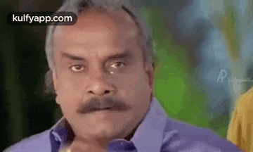 a man with a mustache is making a funny face and looking at the camera .