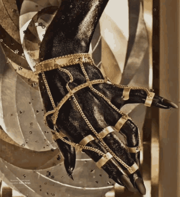a black hand with gold chains on it