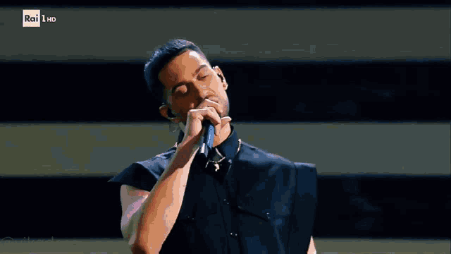 a man singing into a microphone with rai hd on the bottom right