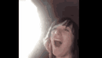 a woman is screaming in the dark with her mouth open .