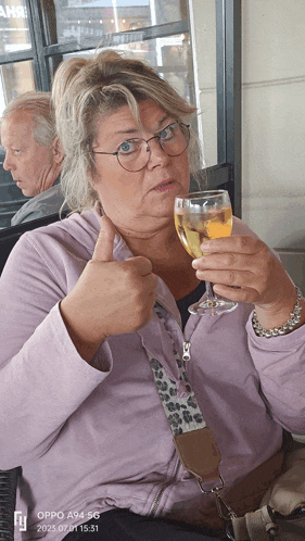 a woman giving a thumbs up while holding a wine glass