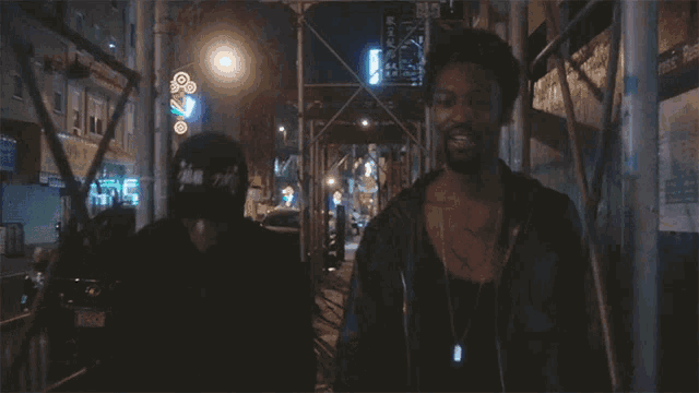 a man wearing a hat that says ' chicago ' on it walks down a street with another man