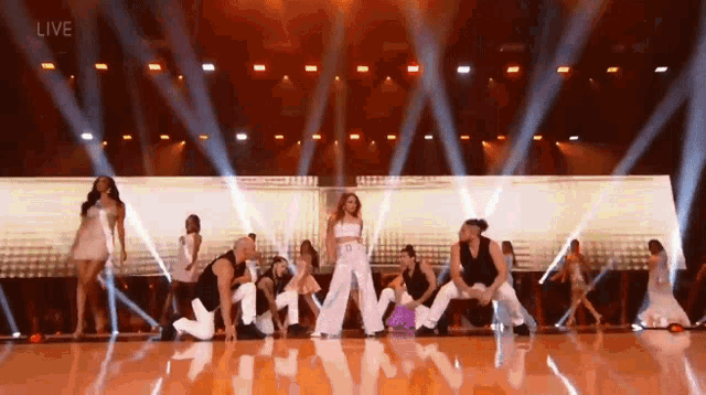 a group of dancers are performing on a stage in front of a live audience