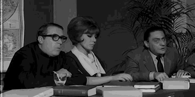 a group of people are sitting around a table with books on it