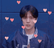 a man in a blue jacket is making a heart with his hands .