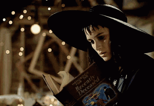 a woman in a witch costume is reading a handbook for the recently deceased