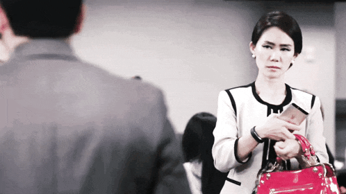 a woman holding a red purse and a cell phone