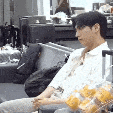 a man is sitting in a chair with a bag of candy in his hand .