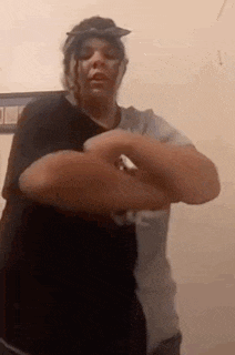 a woman is standing in a room with her arms crossed and a bandana on her head .