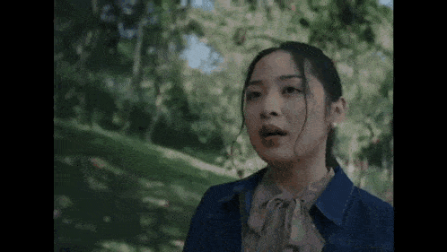 a woman is standing in a park with trees in the background .