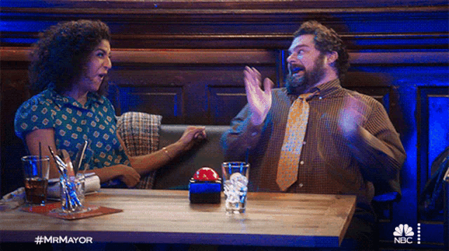 a man and a woman are sitting at a table with nbc written on the bottom