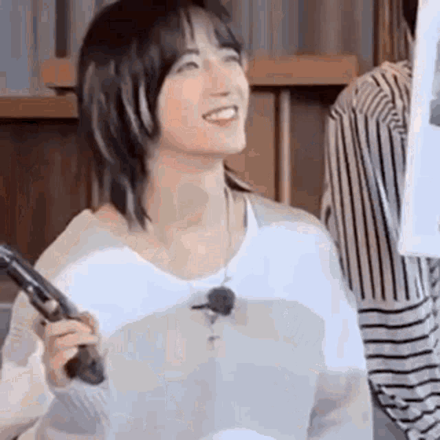 a woman is smiling and holding a microphone in her hand .