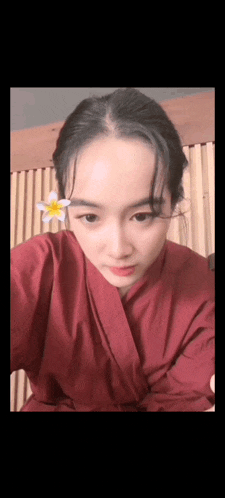 a woman in a red robe with a flower in her hair .