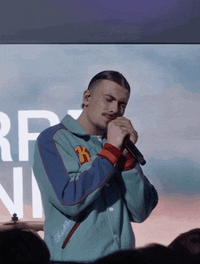 a man singing into a microphone in front of a screen that says rf on it