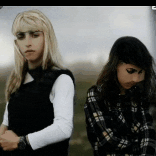 two women are standing next to each other with their arms crossed
