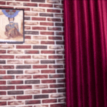 a brick wall with a red curtain and a painting on it