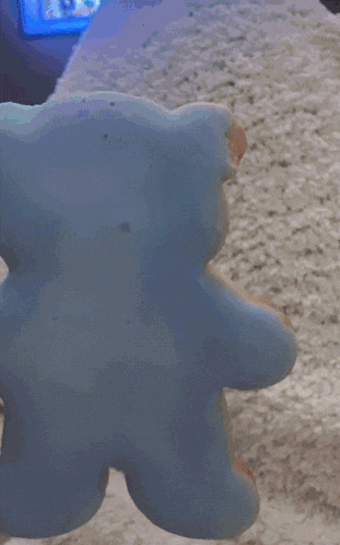 a person is holding a cookie with a bite taken out of it in front of a tv