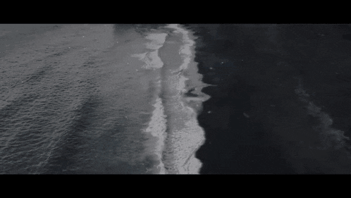 a black and white photo of waves crashing on the beach