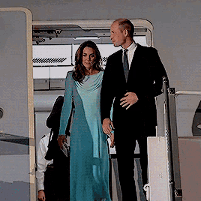 a man in a suit and tie and a woman in a blue dress are standing next to each other