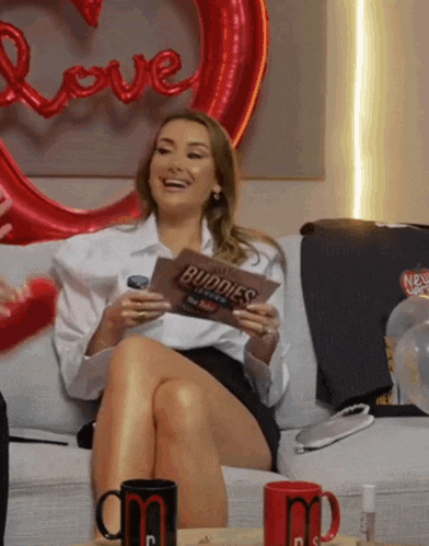 a woman sitting on a couch with her legs crossed holding a card that says buddies
