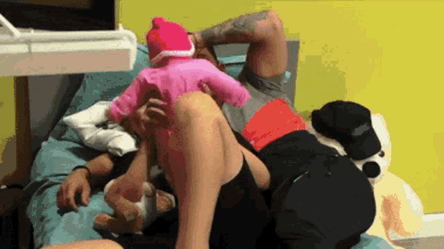 a man is laying on a bed holding a baby