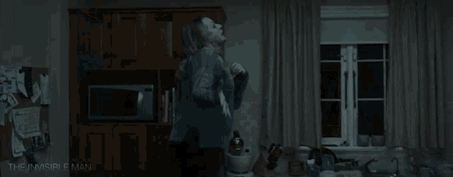 a woman is screaming in a dark room in front of a refrigerator in a movie .