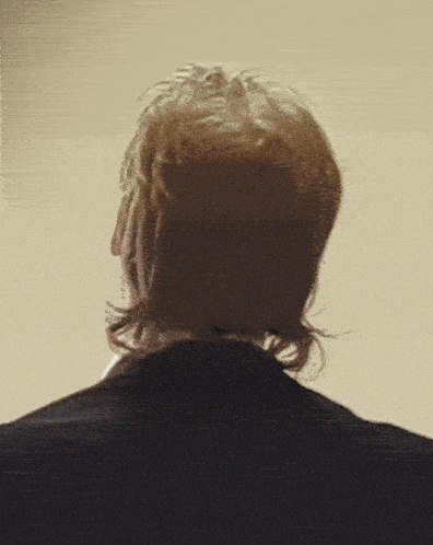 a man with a mullet is wearing a suit and a white shirt