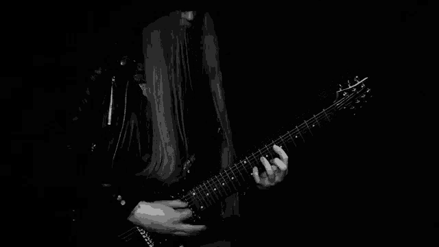 a woman with long hair is playing a guitar in a black and white photo .