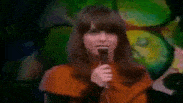 a woman is singing into a microphone on a stage .