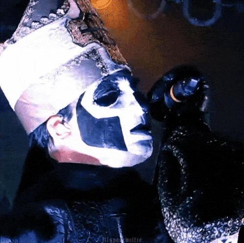 a man with a mask on his face is holding a microphone in his hand .