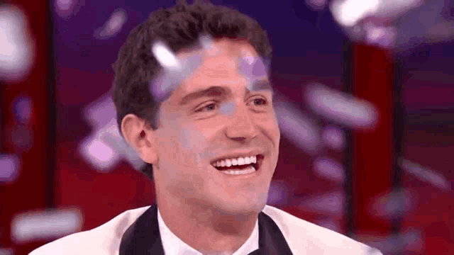 a man in a tuxedo and bow tie is smiling