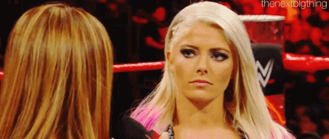 a woman is standing next to another woman in a wrestling ring .