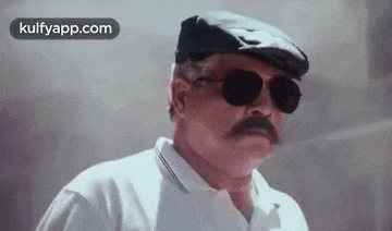 a man with a mustache and sunglasses is wearing a white shirt and a hat .