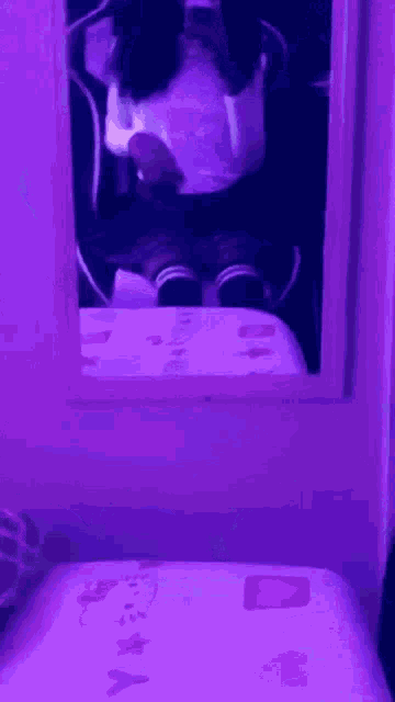 a girl is taking a selfie in front of a mirror in a room with purple lights .