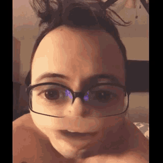 a man wearing glasses and a bun is making a face .