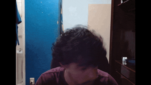 a person 's head is visible in a dark room with a blue wall