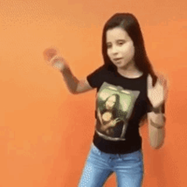 a girl wearing a black t-shirt with a picture of mona lisa on it is dancing in front of an orange background .