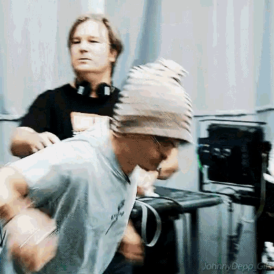 a man wearing a beanie is dancing in front of a dj named johnny depp