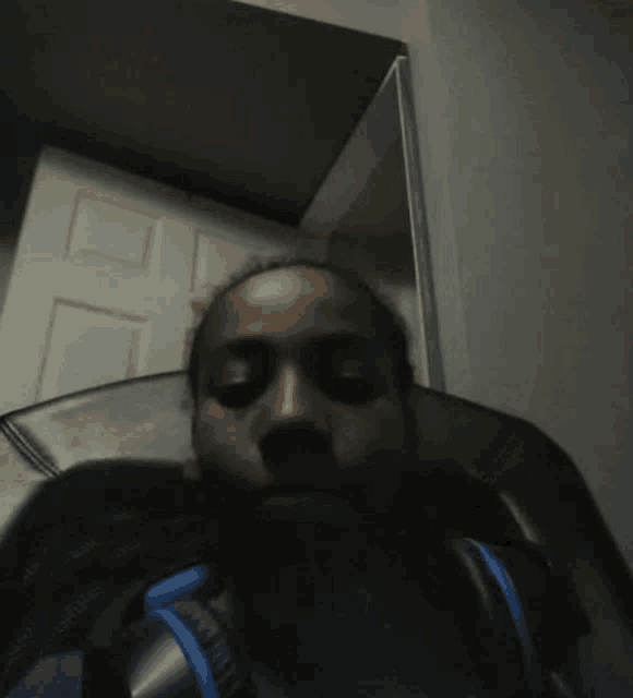 a person is sitting in a chair with their eyes closed and a backpack on their back .