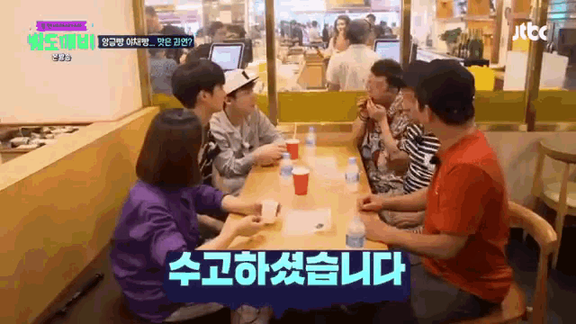a group of people are sitting at a table with a sign that says jtbc on it