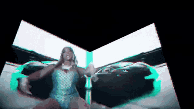 a woman in a blue dress is dancing in front of a screen .