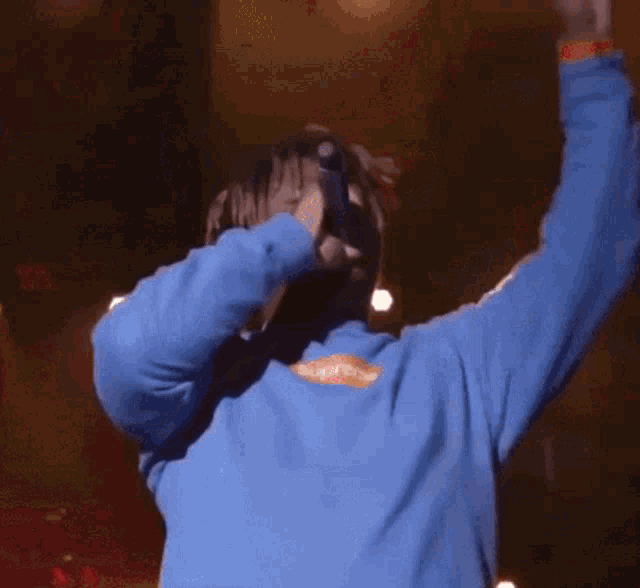 a man wearing a blue supreme sweatshirt is singing on stage .