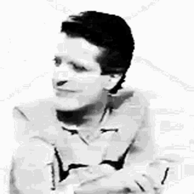 a black and white photo of a man wearing a tie and a shirt .