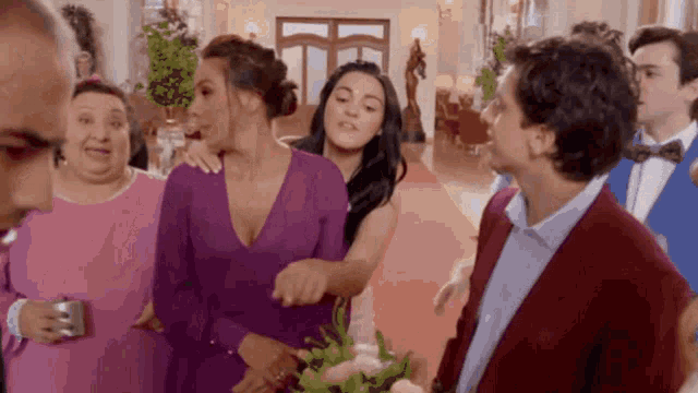 a woman in a purple dress is holding a bouquet of flowers