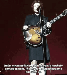 a man in a kilt is playing a guitar and singing into a microphone ..