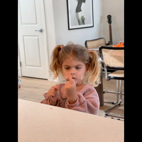 a little girl is sitting at a table with her middle finger up