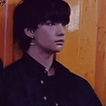 a young man is leaning against a wooden wall and looking at the camera .