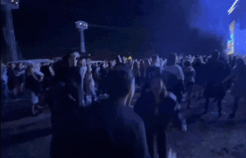 a crowd of people are dancing in a dark room with blue lights