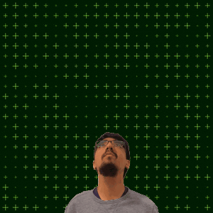 a man wearing glasses stands in front of a green background with the number 1 + 3 on it