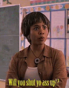a woman is standing in front of a chalkboard and says will you shut yo ass up ?